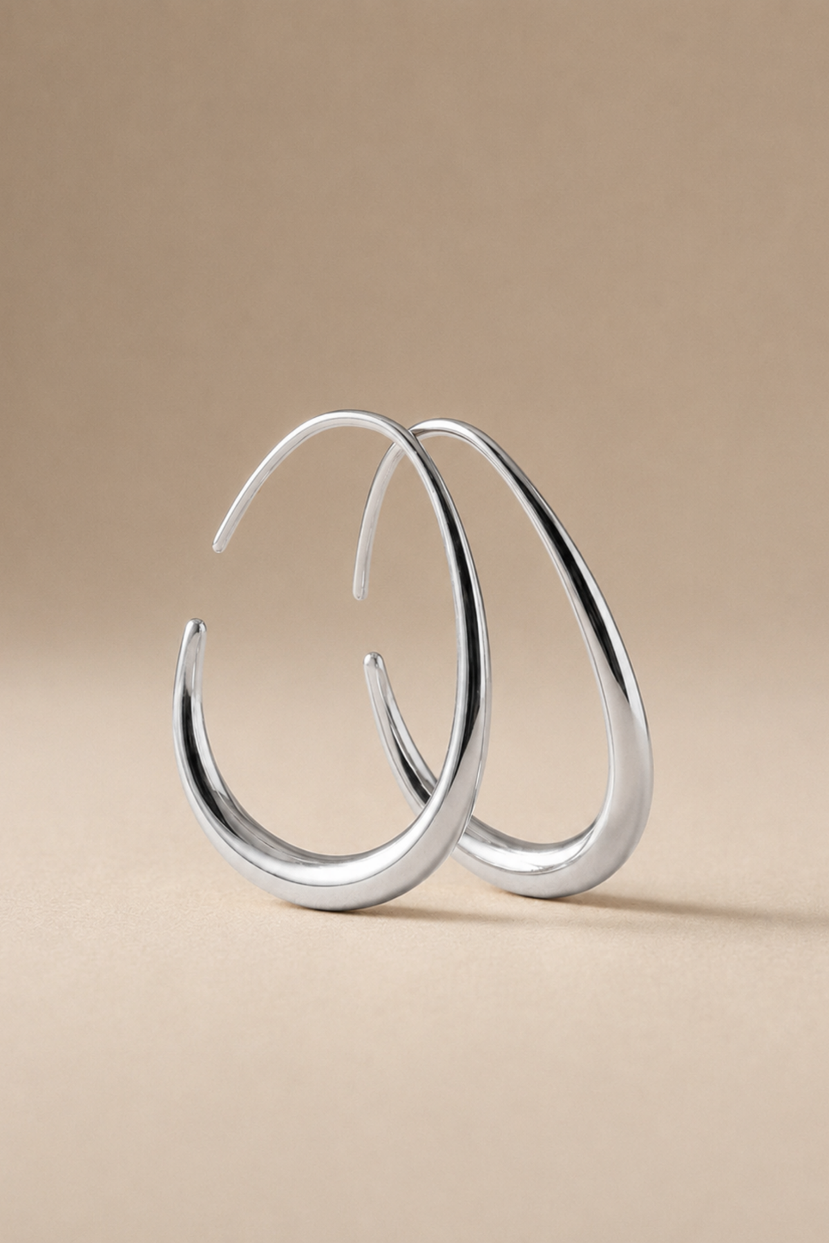Maia silver teardrop hoops on a plain ground