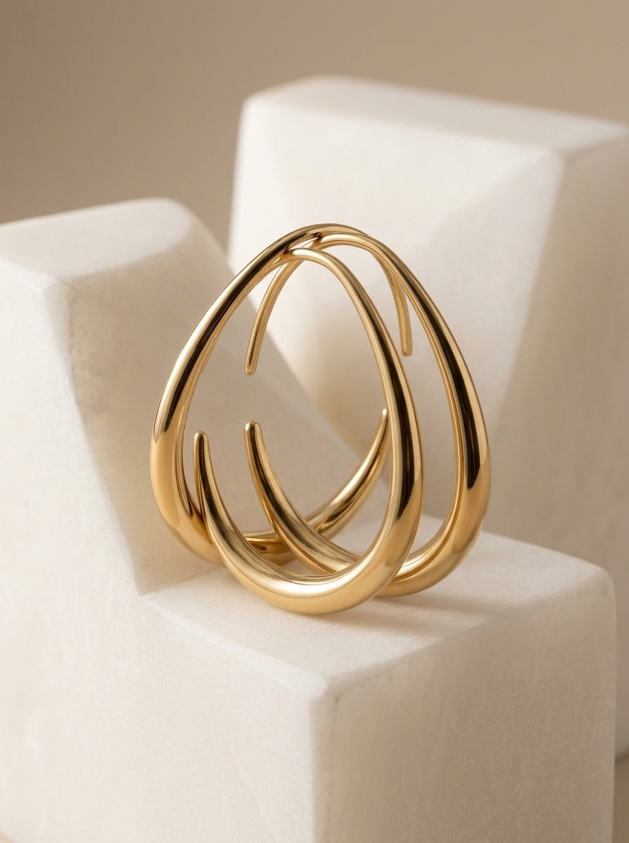 Maia gold teardrop hoops on a stone block