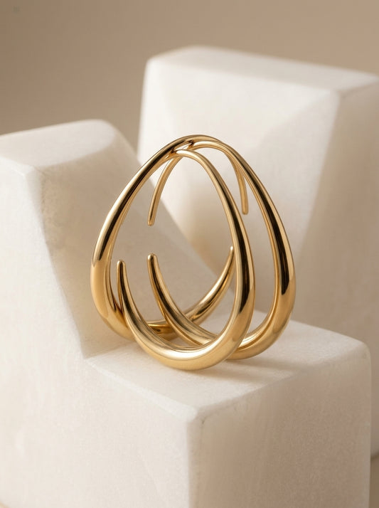 Maia gold teardrop hoops on a stone block